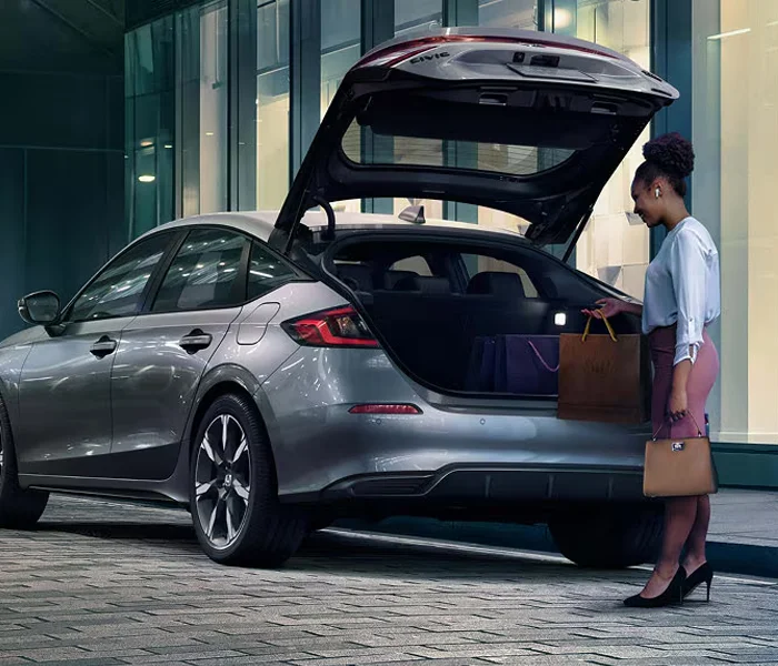 Woman puttinng bags into trunk of a Honda Civic Hatchback